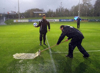 Referee Neil Doyle takes a look at the playing surface in Belfield earlier this evening.