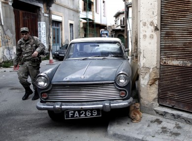 A Greek Cypriot soldier walks at the old town of the capital Nicosia, on Friday, March 29, 2013. Banks in Cyprus are open for normal business for the second day, but with strict restrictions on how much money their clients can access, after being shut for nearly two weeks.