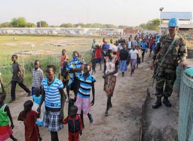 In this handout image from the United Nations Mission in South Sudan taken on Tuesday, Dec. 17, 2013 a United Nations soldier stands guard as civilians arrive at UNMISS compound adjacent to the Juba International Airport to take refuge.